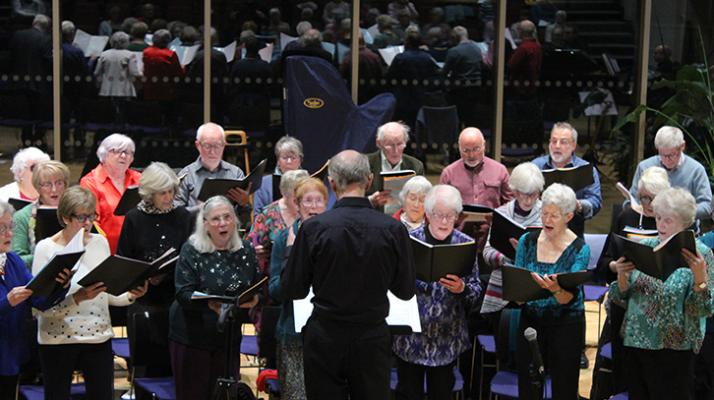 Members of Singing for Pleasure standing up and singing, led by their musical director