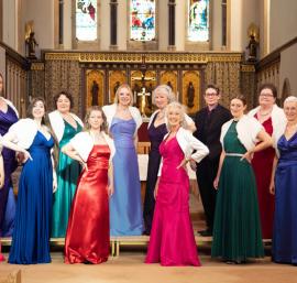 A group of singers wearing colourful evening gowns standing in a church