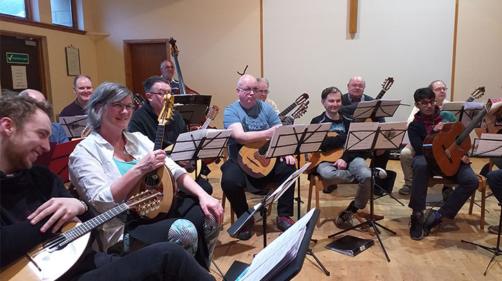 musicians of da capo alba sitting down with their instruments in a semi-circle