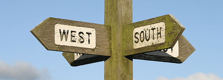 A wooden signpost with four arms pointing North, East, South and West