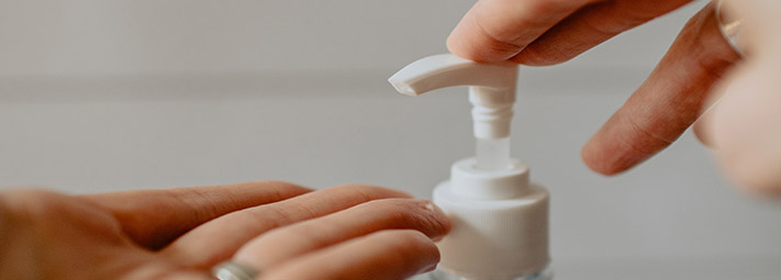 A pair of hands operating a pump action soap dispenser