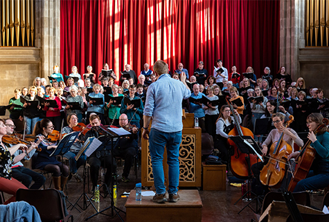 musicians performing in a church with director conductor, facing away from camera