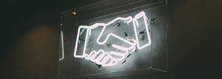 a neon sign comprising two hands shaking each other