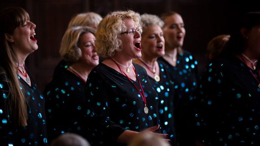 women singing in a group wearing matching black jumpers 