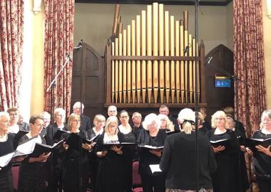 People in a choir standing and holding music scores