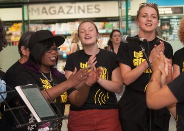 group of people singing and clapping, looking happy in station foyer