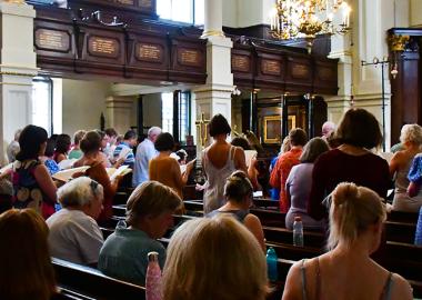 people standing in a church singing from sheet music