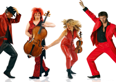 Quartet holding instruments, wearing red coloured outfits, pictured against white backdrop