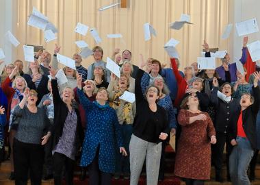 members of the choir throwing sheets of music in the air