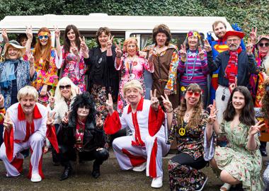 band members wearing colourful hippie clothing and posing to the camera