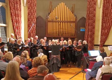 Members of Voices of Exmoor standing and singing in front of an audience