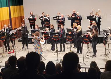 Members of Bedfordshire Woodwind Academy Flute Ensemble standing on a stage and performing