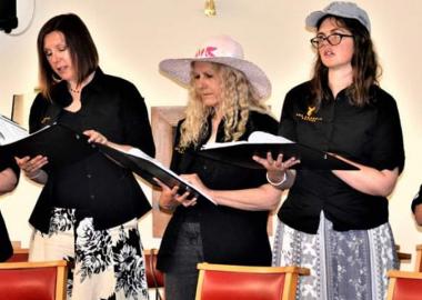 members of the choir standing up, holding their music scores and singing