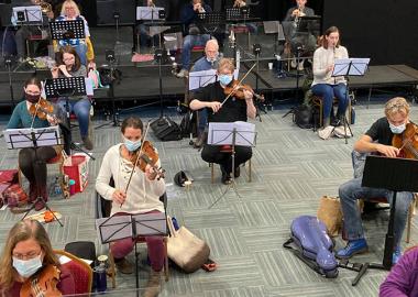 The film Orchestra rehearse, masked and socially distanced