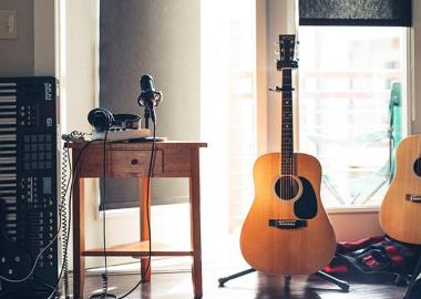 three guitars, mixing equipment and a keyboard lined up in an apartment