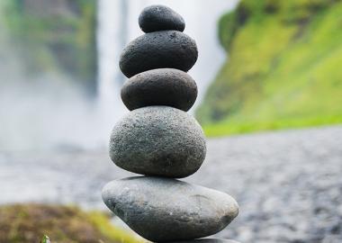 Rocks stacked in a tower against a natural waterfall background