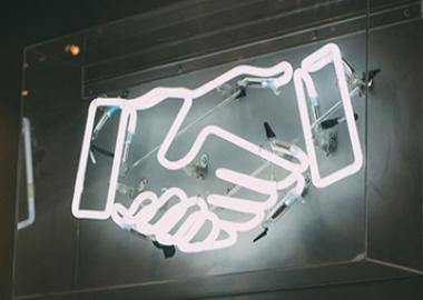 a neon sign comprising two hands shaking each other