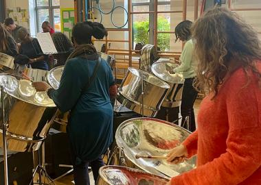 members of the band standing up in front of their instruments during rehearsal indoors