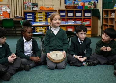 five children sitting next to each other, one with a music instrument in lap