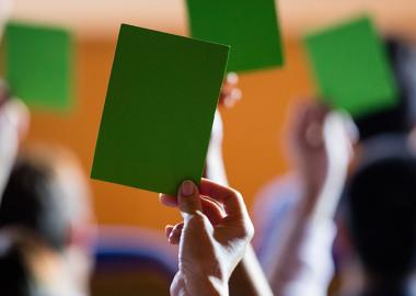 Individuals lifting green voting cards